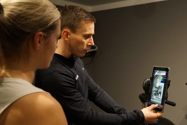 Trainer und Sportlerin besprechen die Laufaufnahmen auf einem Tablet